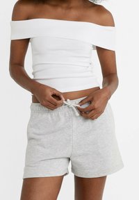 Witte off-shoulder top met een fitted ontwerp; grijze shorts met elastische tailleband en drawstring, zachte textuur en casual stijl.