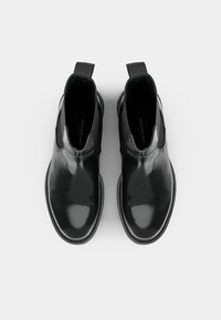 Fekete bőr Chelsea csizma fényes felülettel, rugalmas oldalsó panelekkel és húzófülekkel. Varrt részletek a talp körül.