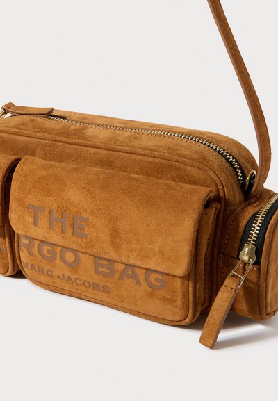 Τσάντα χιαστί από σουέντ σε καμηλό απόχρωση με χρυσούς μεταλλικούς λεπτομέρειες, διαθέτει φερμουάρ, μπροστινή τσέπη και ανάγλυφη λεπτομέρεια με κείμενο. Περιλαμβάνεται ρυθμιζόμενο λουρί.