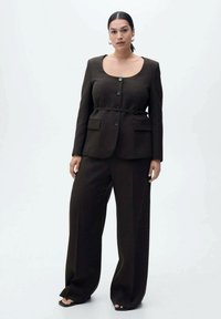 Completo marrone a due pezzi con giacca aderente a scollo tondo e cintura, abbinato a pantaloni a gamba larga. Tessuto liscio e design strutturato.