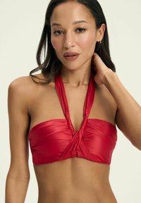 Czerwony bikini górny wykonany z gładkiego materiału, z halterowym krojem, twisted front i regulowanymi ramiączkami.
