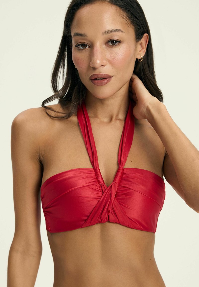 Czerwony bikini górny wykonany z gładkiego materiału, z halterowym krojem, twisted front i regulowanymi ramiączkami.