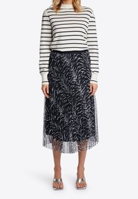 Randig långärmad tröja i krämfärgad och navy, matchad med en svartvit zebramönstrad tyllkjol, avslutad med silverfärgade sandaler.