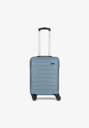 Valise rigide de couleur bleu clair, dotée d'une texture rainurée, d'une poignée rétractable et de quatre roues noires pour la mobilité.