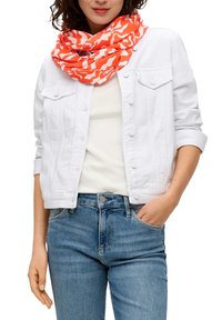 Witte denimjack, wit t-shirt en blauwe jeans. De sjaal is oranje met witte abstracte patronen, rondom de nek gedrapeerd.