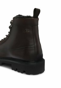 Bruine leren enkellaars met een gestructureerde afwerking, metalen oogjes, nepbontvoering bij de enkel en een stevige zwarte rubberen zool.