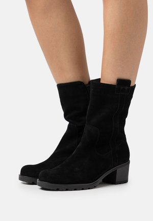 Black suede ankle boots with a moderate heel, featuring a side zipper and a textured sole. The design is streamlined with subtle stitching.