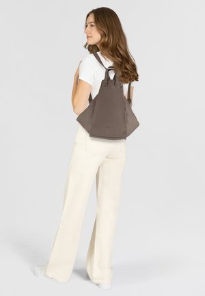 Brown triangular backpack made of soft material, featuring dual straps, minimalistic design, and an embossed logo at the base.