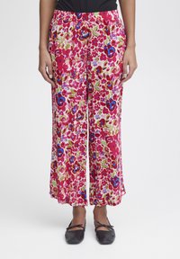 Pantalons à imprimé floral en rose, vert et bleu ; fabriqués en tissu léger avec une taille élastique et un design à jambes larges.