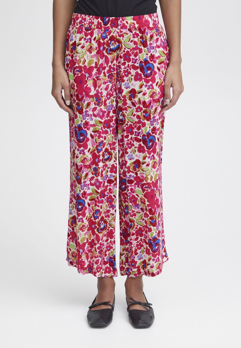 Pantalons à imprimé floral en rose, vert et bleu ; fabriqués en tissu léger avec une taille élastique et un design à jambes larges.