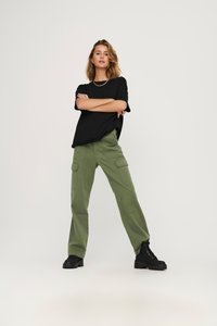 Sort oversized t-shirt med korte ærmer, parret med olivengrønne cargo bukser med flere lommer. Sorte chunky støvler.