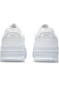 Scarpe sportive bianche con tomaia in pelle liscia, dettagli texture e suola bianca ammortizzata. Presentano un tacco arrotondato e un dettaglio con logo sulla parte posteriore.