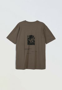 Brązowa bawełniana koszulka z krótkim rękawem, z czarnym abstrakcyjnym nadrukiem na plecach, prostokątnym wzorem i luźnym krojem.