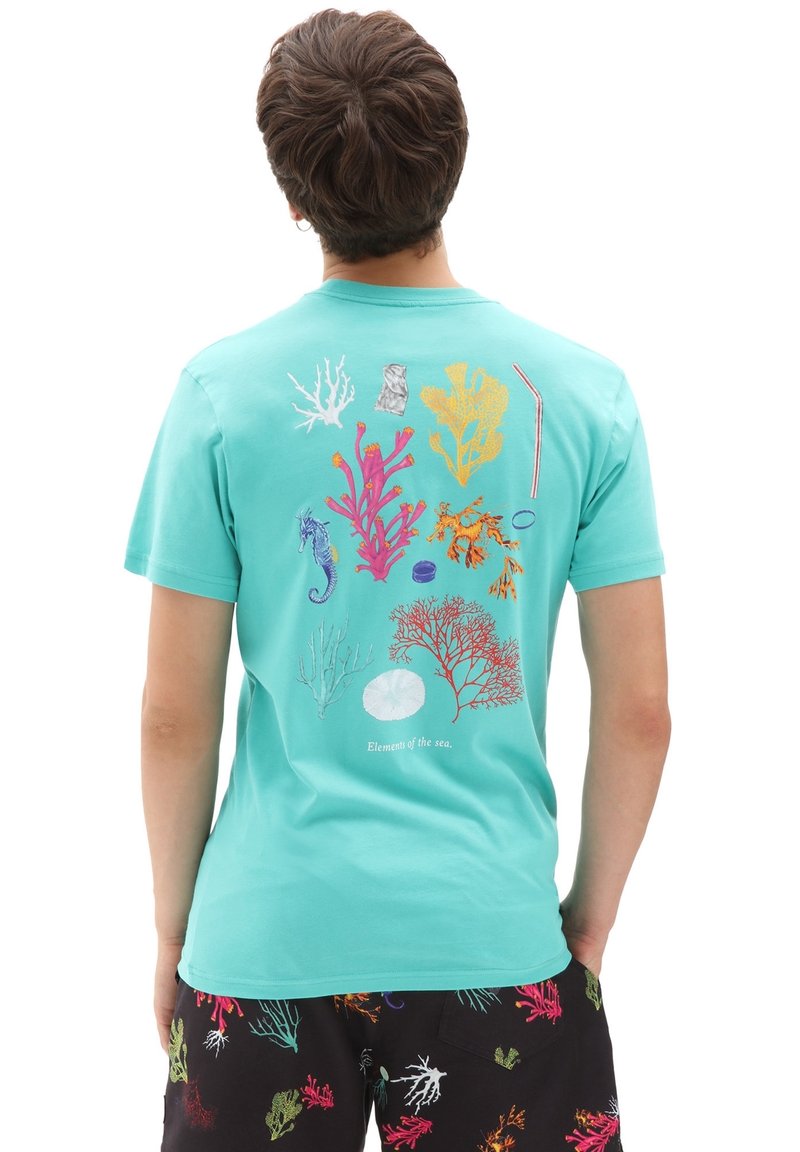 Homme portant un t-shirt turquoise avec des illustrations colorées d'algues marines et d'hippocampes, ainsi qu'un short noir aux motifs coralliens, debout de dos.