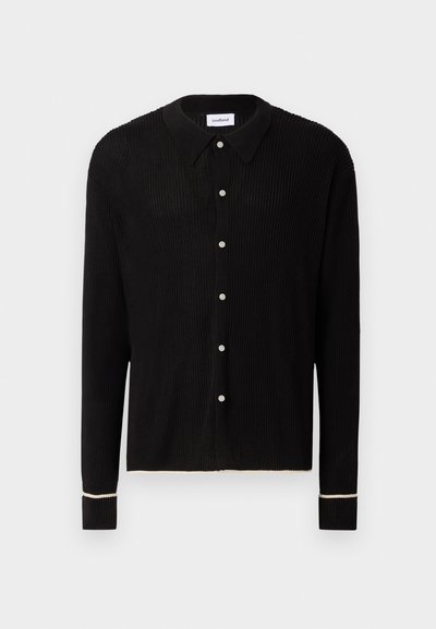 Cardigan negru din tricot cu pliuri, guler, butoane argintii și cusături albe pe manșete și tiv. Croi obișnuit, cu mâneci lungi.