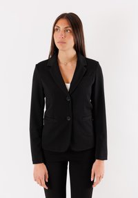 Blazer nero con un design aderente, caratterizzato da un rever a punta, due bottoni e tasche frontali. Tessuto liscio e maniche lunghe.