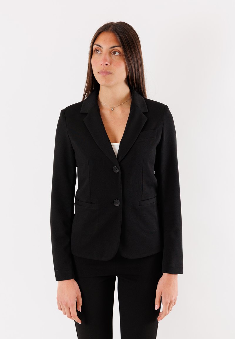 Blazer nero con un design aderente, caratterizzato da un rever a punta, due bottoni e tasche frontali. Tessuto liscio e maniche lunghe.