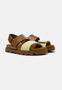 Brown and yellow leather sandals with two adjustable straps, soft footbed, and a chunky, textured rubber sole. Open design for breathability.