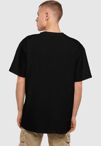 Sort T-shirt i afslappet pasform, kortærmet, rund hals, lavet af bomuld. Synlige sømdetaljer ved ærme- og kravekanter.