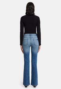 Blauwe denim flare jeans met een gemiddelde taille, lichte vervaging en twee achterzakken. De stof heeft een gladde textuur met een klassieke afwerking.