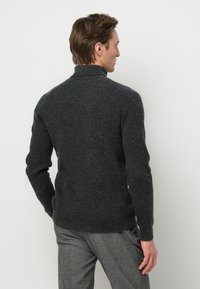 Dunkelgrauer, strukturierten Strickpullover mit hohem Kragen und figurbetonter Silhouette, der gerippte Muster im Stoff zeigt. Nur Rückansicht.