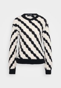 Svart og hvit strikket genser med diagonale bølgende striper, ribbestrikkede mansjetter, kant og rund hals, vist mot en enkel bakgrunn.
