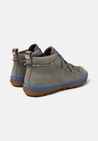 Zapatos gris de caña alta con suela azul y tela texturizada, que muestran cordones y un diseño duradero para uso al aire libre.