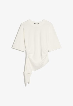 Biały top z krótkim rękawem, okrągłym dekoltem i asymetrycznym, drapowanym detalem zwisającym po lewej stronie.