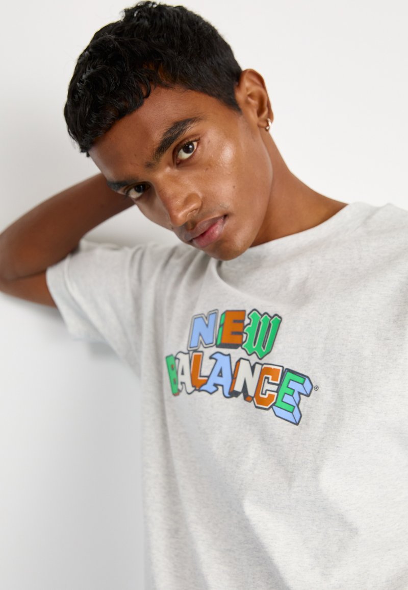 Grijze katoenen t-shirt met een multicolor "NEW BALANCE" logo. Korte mouwen, losse pasvorm, ronde hals, gladde textuur.