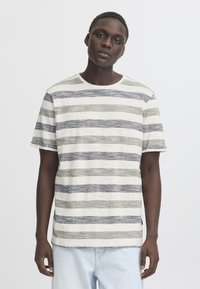 Randig t-shirt med korta ärmar, med växlande tunna blå, gröna och beige ränder, rund halsringning och mjukt texturerat tyg.