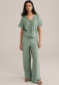 Completo due pezzi verde chiaro composto da una camicia a maniche corte con bottoni e pantaloni a gamba larga, realizzato in tessuto testurizzato con una vestibilità comoda.