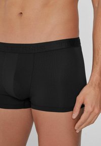 Černé boxerky vyrobené z hladké, elastické tkaniny. Elastický pas má zdvižené písmové provedení. Přiléhavý design zvýrazňuje postavu.