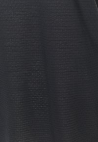 Tissu tricoté noir avec un motif texturé de lignes horizontales et de petits points en relief, montrant un matériau doux et extensible.