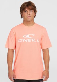 Camiseta de O'Neill de color rosa claro, con mangas cortas, escote redondo y un gran logo blanco en el pecho. Tejido suave y corte relajado.