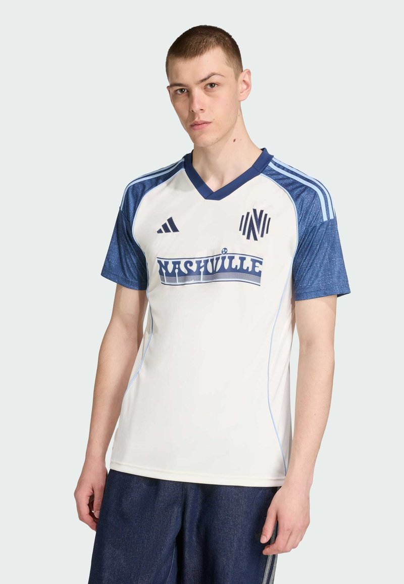 Vit atletisk tröja med blå detaljer, V-ringad hals, korta ärmar, med "NASHVILLE"-logotyp på framsidan och tre-stripes design på axlarna.