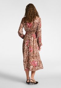 Abito midi a stampa floreale marrone con maniche lunghe, vita cintrata e tessuto testurizzato con dettagli rosa e bianchi.
