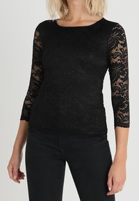 Black lace top with 3/4 sleeves, featuring floral patterns and a scalloped hem. Made of textured lace material, fitted design.