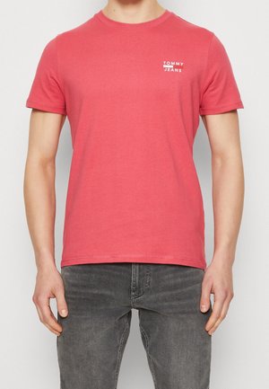 Czerwona bawełniana koszulka z okrągłym dekoltem i krótkimi rękawami, z małym białym logo "TOMMY JEANS" na lewej piersi. Gładka faktura.