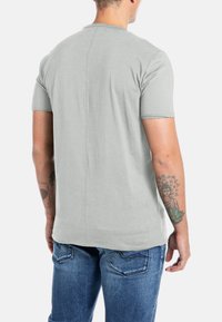 Grijze t-shirt met korte mouwen en een ronde hals, met een rechte pasvorm en een soepele textuur, gecombineerd met blauwe spijkerbroeken.