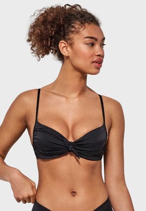 Top de bikini negro con tirantes finos ajustables, que presenta un diseño central anudado. La tela parece suave y con un ligero brillo.