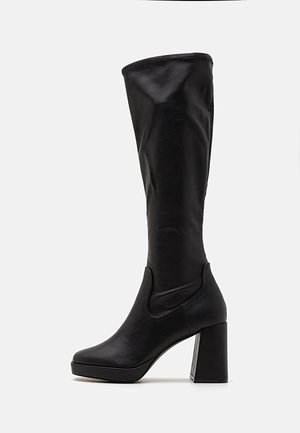 Melnas līdz ceļiem augstas zābaki, izgatavoti no gludas ādas, ar masīlu bloku papēdi un elastīgām sānu daļām, kas nodrošina vienkāršu uzvilkšanu.