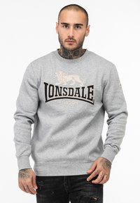 Grijze sweatshirt met lange mouwen, featuring een leeuw graphics en het "LONSDALE LONDON" logo in zwart en beige. Katoenen materiaal met een geribbelde halslijn.