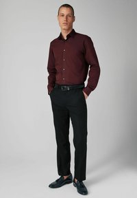 Bordeaux rot langärmliges Hemd mit Button-Down-Kragen, kombiniert mit schwarzen Hosen und dunklen Schuhen. Hat ein tailliertes Design und eine glatte Textur.