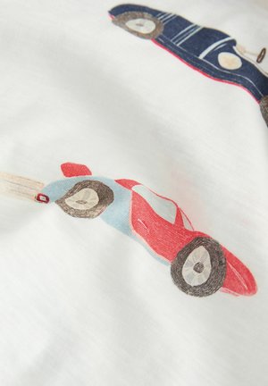 Kaksi leluautoa, yksi punainen ja sininen, joka liikkuu nopeasti liikeviivojen kera, ja toinen sininen vintage-tyylinen, painettuna valkoiselle kankaalle.