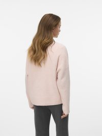 Hellrosa Pullover mit weichem Stoff, überschnittenen Schultern und geripptem Saum. Kombiniert mit grauen Hosen. Von hinten zu sehen.