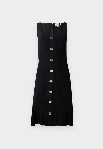 Mustmust ketidress, millel on jäik ülaosa, kuldtoonides nupud esipool ja laineline alläär. Tagaküljel on lukuga sulgemine.