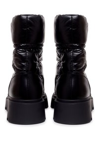 Bottes noires matelassées jusqu'à la cheville avec un bout arrondi, une tige rembourrée et une semelle en caoutchouc épaisse. Texture lisse avec un accent élastique près du haut.