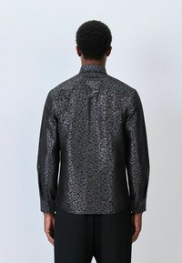 Czarna koszula z delikatnym wzorem w panterkę, z długimi rękawami, standardowym kołnierzykiem i dopasowanym krojem, wykonana z gładkiego materiału.