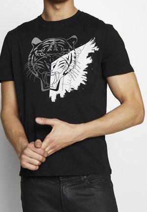 Zwarte katoenen t-shirt met een grafische afbeelding van het gezicht van een tijger in wit en grijs, met een penseelstrekenontwerp. Korte mouwen en een ronde halslijn.