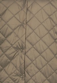 Giacca imbottita trapuntata in tessuto verde oliva, caratterizzata da motivi a diamante, bottoni automatici e una texture liscia e lucida.